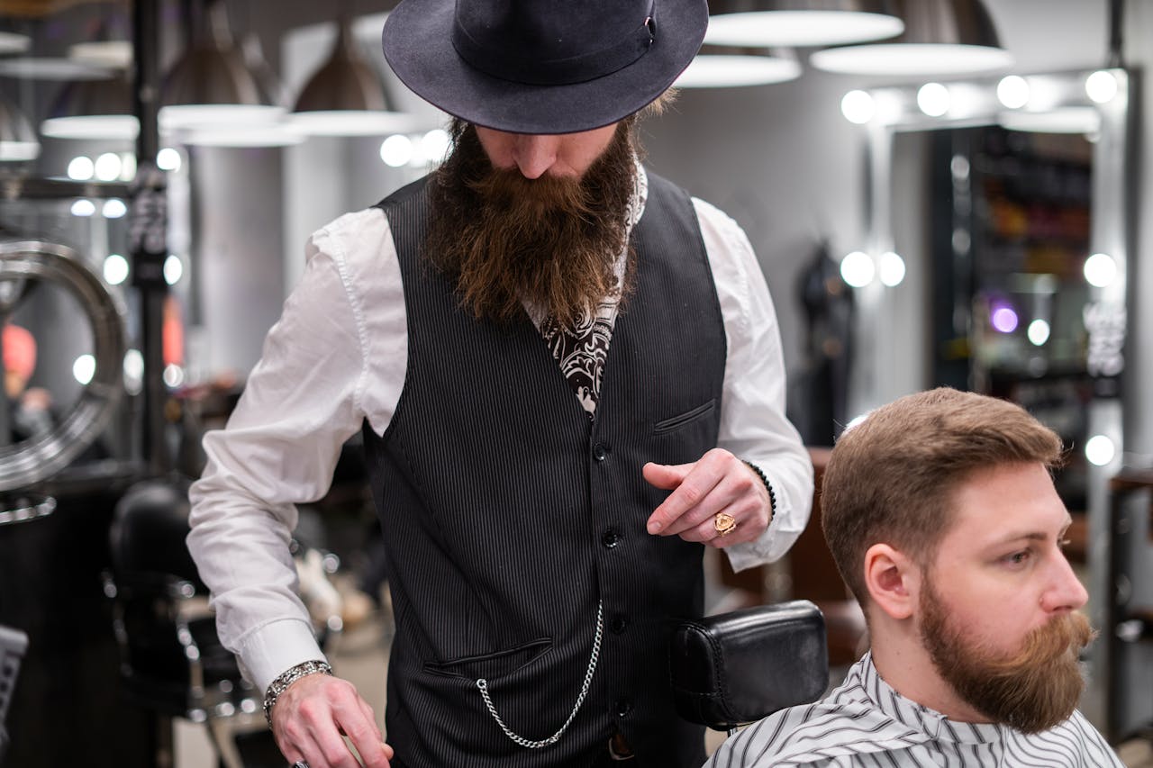 A bearded barber skillfully trims a clients hair in a modern barbershop setting.