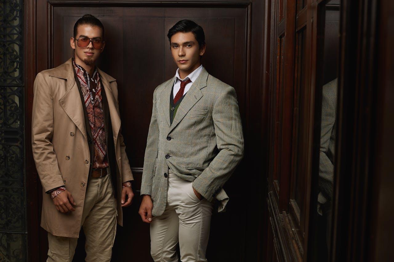 Two men in fashionable suits posing indoors, showcasing elegance and style.